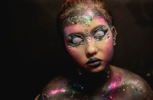 Portrait of young female model with creative makeup,  rhinestones and piercing