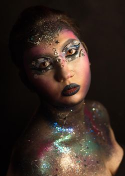 Portrait of young female model with creative makeup,  rhinestones and piercing