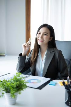 Portrait happy businesswoman sitting at het workplace and smiling to camera.