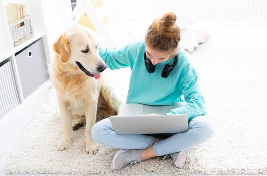 Nice teenage girl working on computer next to cute dog