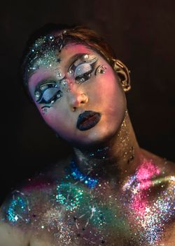 Portrait of young female model with creative makeup,  rhinestones and piercing