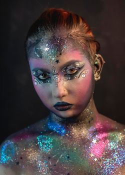 Portrait of young female model with creative makeup,  rhinestones and piercing