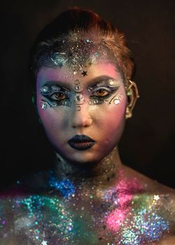 Portrait of young female model with creative makeup,  rhinestones and piercing