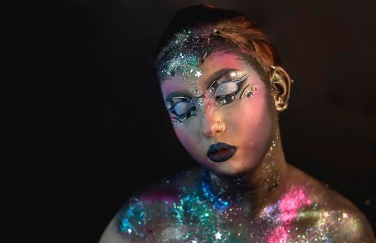 Portrait of young female model with creative makeup,  rhinestones and piercing