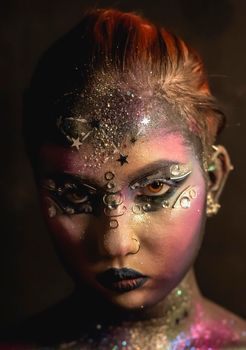 Portrait of young female model with creative makeup,  rhinestones and piercing