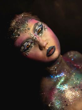 Portrait of young female model with creative makeup,  rhinestones and piercing