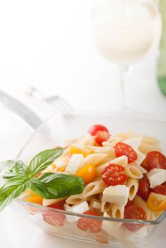 bright and tasty pasta salad with fresh mozarella and cherry tomatoes, basil