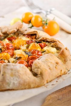 delicious homemade galetta pie with cherry tomatoes, feta cheese and basil and rosmarim herbs