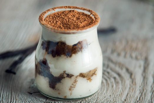 sweet italian desert tiramisu in glass on wooden background