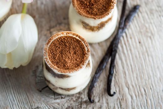 sweet italian desert tiramisu in glass on wooden background