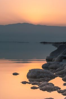 Beautiful sunrise at Dead Sea in Israel wih rocks of salt at foreground