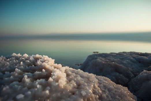 Beautiful sunrise at Dead Sea in Israel wih rocks of salt at foreground