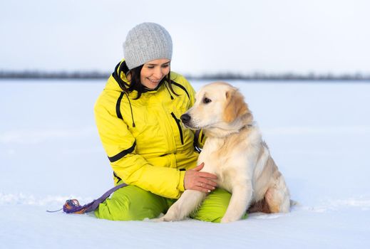 Beautiful girl with lovely young retriever dog outside in winter