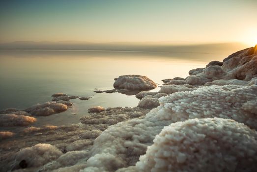 Beautiful sunrise at Dead Sea in Israel wih rocks of salt at foreground