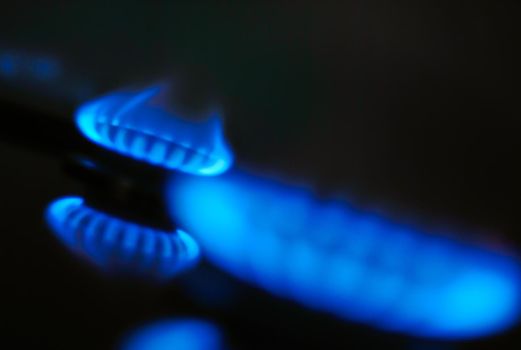 abstract gas burner with blue flame on dark background