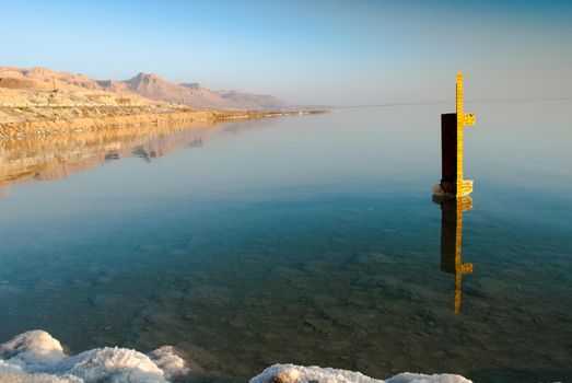Dead Sea in Israel wih rocks of salt at foreground and pillar of water level