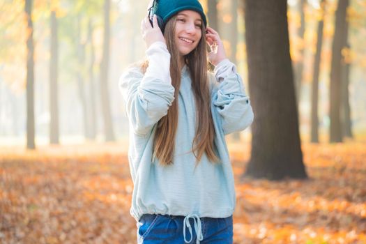 Portrait of pretty girl in headphones on blurred autumn background