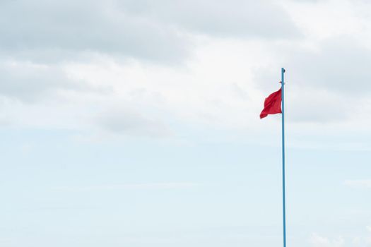 Flag beach warning wind dangerous red blue sky water windy, for white danger from wave from clouds ocean, attention symbol. Atlantic color landscape, swimming rnli