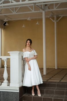 portrait of a young bride girl in a short white dress on a rainy day