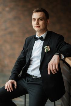 portrait of a young guy groom in a black suit on a rainy day