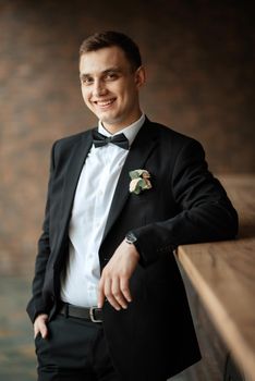 portrait of a young guy groom in a black suit on a rainy day