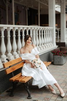 portrait of a young bride girl in a short white dress on a rainy day