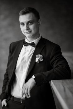 portrait of a young guy groom in a black suit on a rainy day