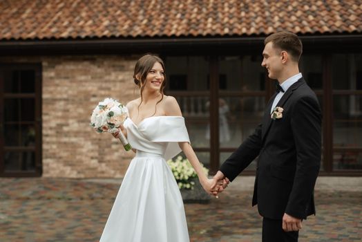 young couple bride and groom in a white short dress walking in the rain