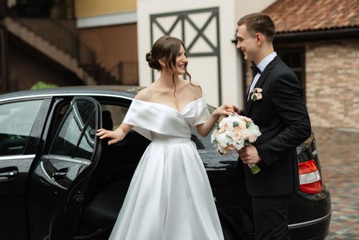 young couple bride and groom in a white short dress walking in the rain