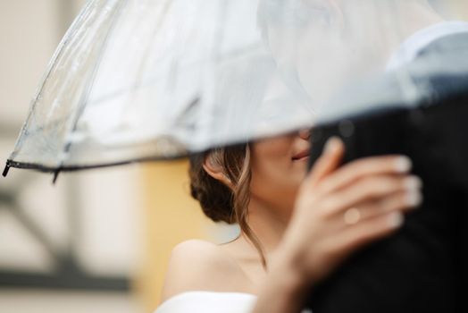 young couple bride and groom in a white short dress walking in the rain