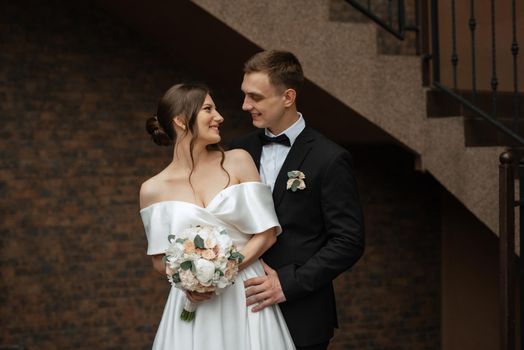 young couple bride and groom in a white short dress walking in the rain