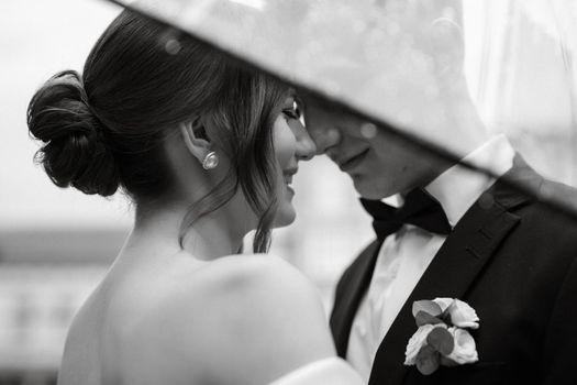 young couple bride and groom in a white short dress walking in the rain