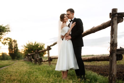 young couple the groom in a black suit and the bride in a white short dress on a walk in the village