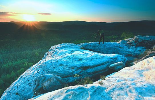 Photographer looks into the landscape and listen the silence. Man prepare camera to takes impressive photos of misty fall mountains.