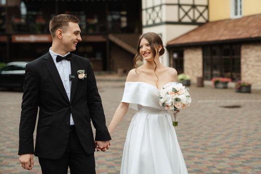 young couple bride and groom in a white short dress walking in the rain