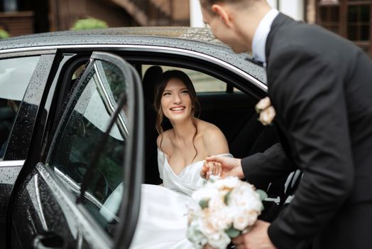 young couple bride and groom in a white short dress walking in the rain