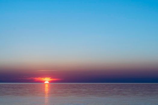 beautiful red sunset sun on the sea on the surface of the water. the bay and the setting summer sun. seascape. sea resort