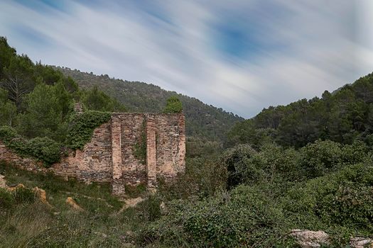 Jinquer, Castellon, Spain. Houses in ruins of an abandoned village in the middle of the vegetation.Mountain, group of houses. roads, Spanish Civil War