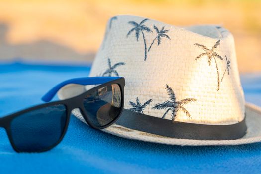 a sun hat and sunglasses on a beach blanket. The concept of summer holidays, vacations and travel. Copy space