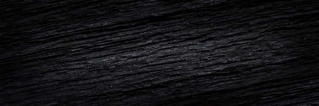 Texture of black old wood. Close-up of the texture of deep black bog oak. Sinuous wood texture with shadow