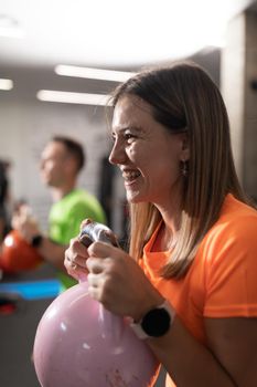 A young woman with braces smiles while doing sport and exercises holding the kettlebell, at the local training and fitness center