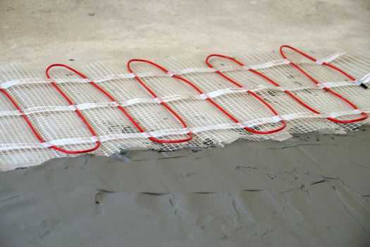 cable electric underfloor heating partially under cement screed close-up