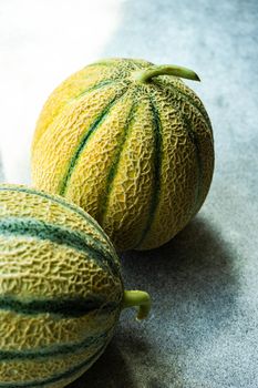 Textured fresh and ripe cantaloupe melons on concrete background