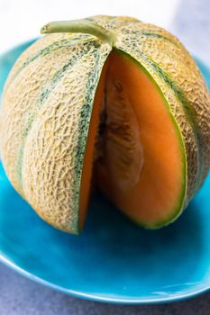 Ripe cantaloupe melon slices on the blue ceramic plates served for dessert meal