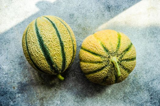 Textured fresh and ripe cantaloupe melons on concrete background