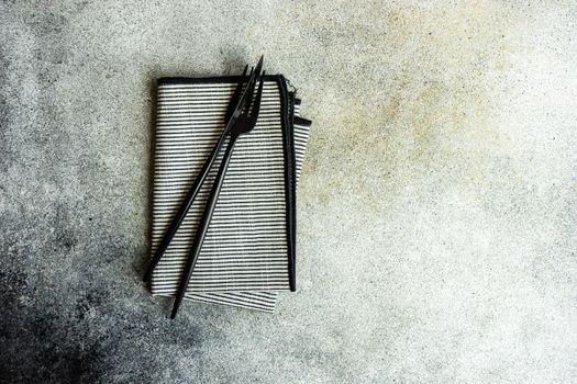 Cutlery set with textile napkin and silverware on concrete table