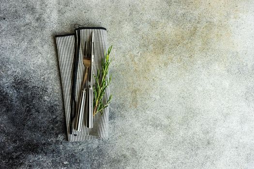 Cutlery set with textile napkin and silverware on concrete table