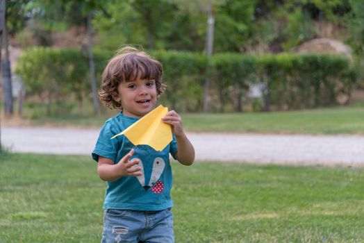 Happy kid playing with toy airplane against summer sky background at sunset