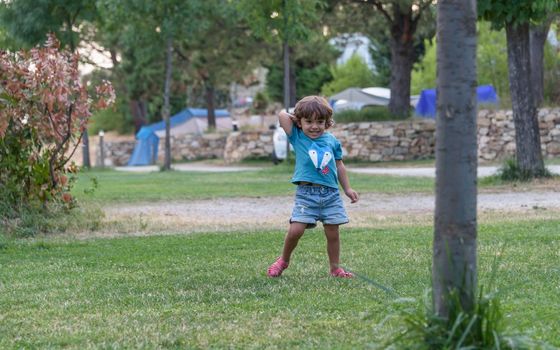 Happy kid playing with toy airplane against summer sky background at sunset