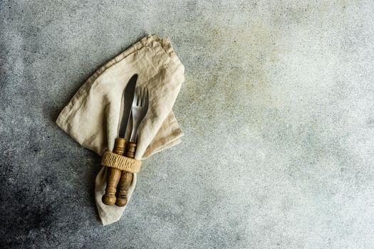 Cutlery set with textile napkin and silverware on concrete table